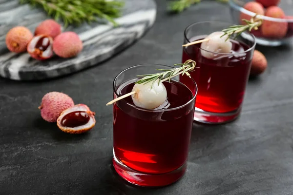 有迷迭香和新鲜水果的美味荔枝鸡尾酒放在黑桌上 — 图库照片