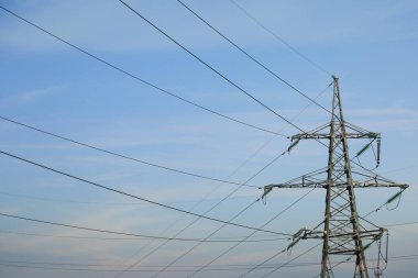 Güneşli bir günde mavi gökyüzüne karşı yüksek voltaj kulesi