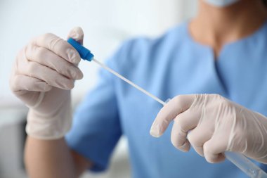 Klinikte DNA testi için pamuklu çubuk ve tüp tutan doktor.