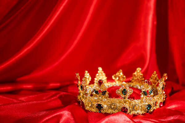 Beautiful golden crown on red fabric, space for text. Fantasy item