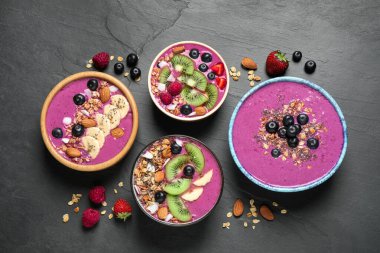 Acai smoothie kaseleri granola ve siyah masada meyveler, düz uzanma
