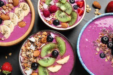 Acai smoothie kaseleri granola ve siyah masada meyveler, düz uzanma