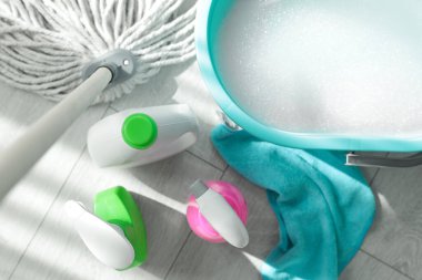 Kova, paspas ve yerde farklı temizlik malzemeleri var.