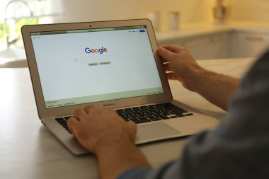 MYKOLAIV, UKRAINE - 27 Ekim 2020: İçerideki masada MacBook Air dizüstü bilgisayarında Google arama motoru kullanan adam, yakın plan