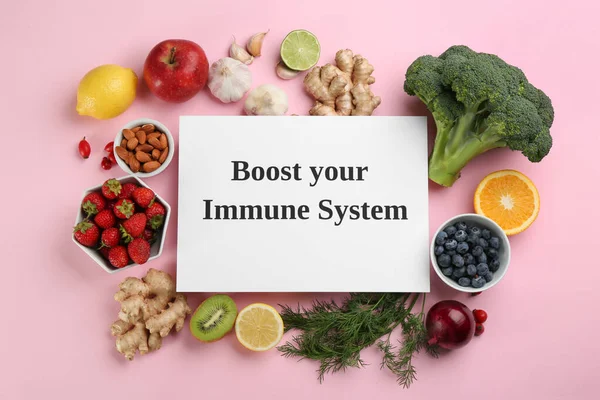 Pembe zemin üzerinde bağışıklık sisteminizi güçlendiren metin içeren doğal ürünler ve kağıt tabaka kümesi düz yatar