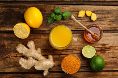 Bağışıklık güçlendirici içecek ve ahşap masa malzemeleri içeren düz bir kompozisyon.