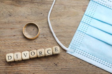 Düz kompozisyon, koruyucu maske ve alyans takılı ahşap masa. Koronavirüs karantinası sırasında boşan