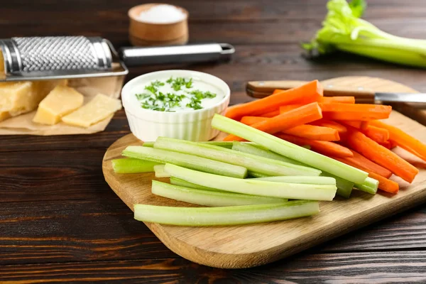 Celery and carrot sticks with dip sauce on wooden table