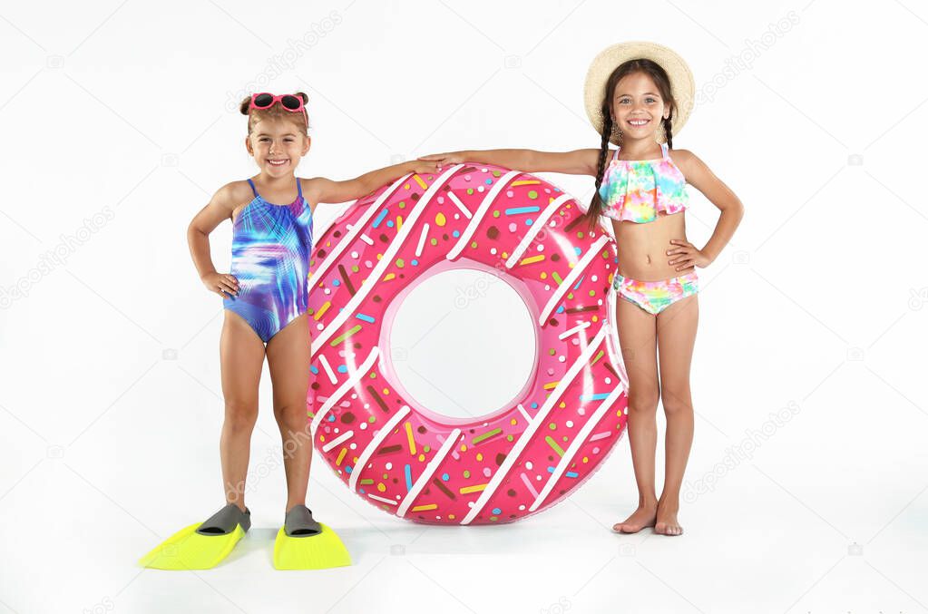 Cute little children in beachwear with bright inflatable ring on white background