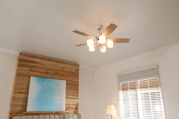 Modern ceiling fan with lamps in room, low angle view