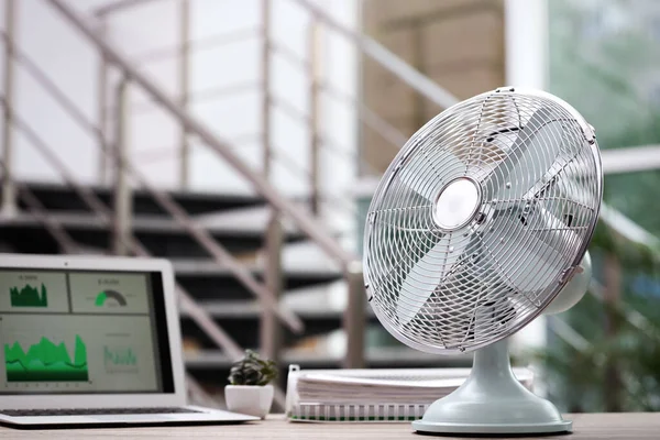 Modern electric fan on table in office. Space for text