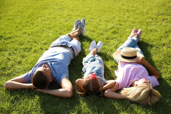 快乐的父母带着孩子躺在绿草上 在性质上花费的时间 — 图库照片