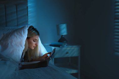 Geceleri yatakta tablet kullanan genç bir kadın. Uyku bozukluğu sorunu