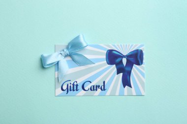 Açık mavi arkaplanda fiyonklu hediye kartı, üst görünüm