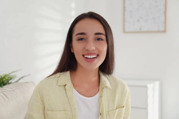 Young woman talking with her coworkers on video call indoors, view from web camera