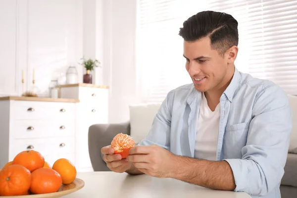 Hombre Feliz Pelando Mandarina Mesa Interior —  Fotos de Stock