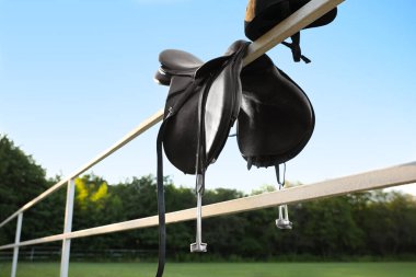 Dışarıdaki ahşap çitin üzerinde deri at eyeri.