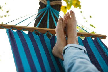 Yeşil bahçedeki hamakta dinlenen adam, yakın plan.