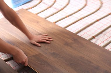 İşçi yeni ahşap kaplamaları zemin altı ısıtma sisteminin üzerine yerleştiriyor, kapatıyor