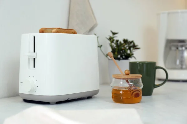 现代烤面包机 厨房白桌上放着面包片和蜂蜜 — 图库照片