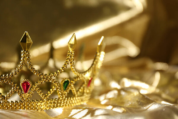 Beautiful ancient crown on golden fabric, space for text. Fantasy item