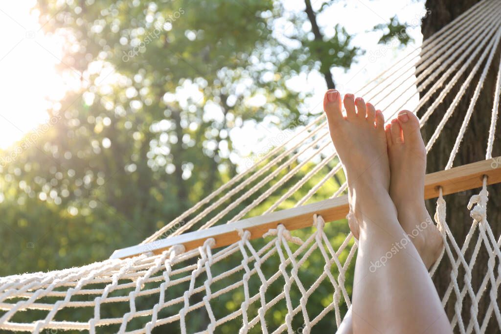 Woman resting in comfortable hammock at green garden, closeup