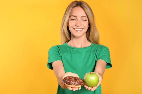 Mujer Eligiendo Entre Donut Manzana Sana Sobre Fondo Amarillo — Foto de Stock