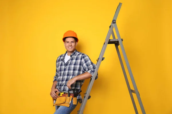 Professionelle Bauarbeiter Der Nähe Von Metallleiter Auf Gelbem Hintergrund — Stockfoto