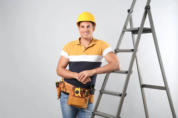 Professionele Bouwer Bij Metalen Ladder Grijze Achtergrond — Stockfoto
