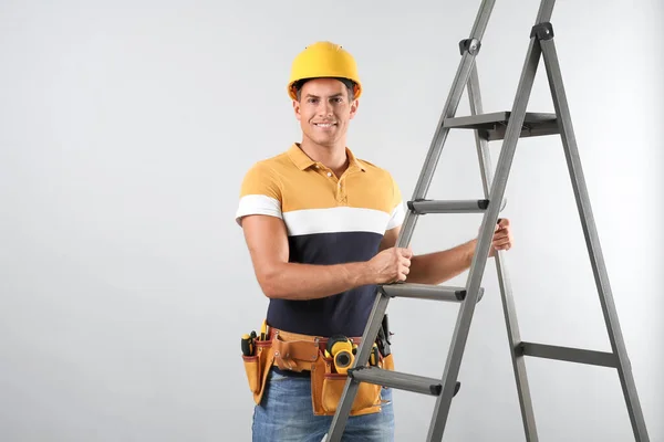 Professionele Bouwer Met Metalen Ladder Grijze Achtergrond — Stockfoto