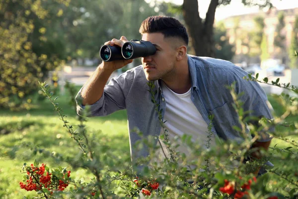 Jealous man with binoculars spying on ex girlfriend in park