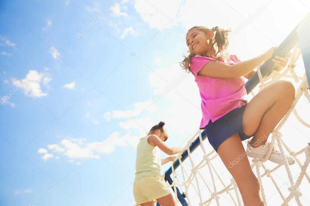 Cute children on playground rope climber outdoors. Summer camp