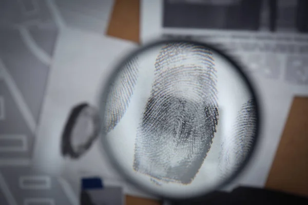 Looking through magnifying glass at fingerprints on detective board, closeup