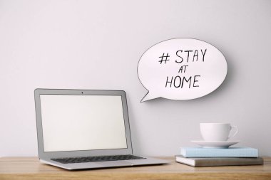 Laptop, fincan ve hashtag ile konuşma balonu Evde Kal. Covid19 salgını sırasında kendini izole etmeyi teşvik eden mesaj