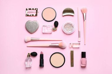 Pembe arka planda makyaj fırçaları ve kozmetik ürünleri, düz konum
