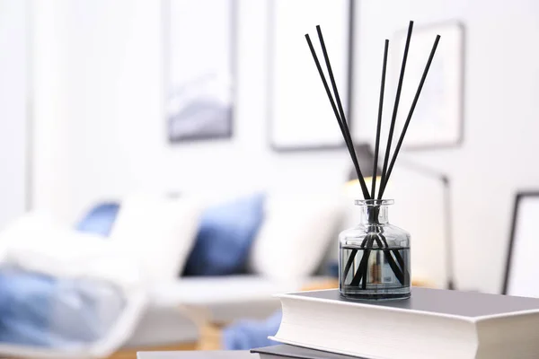 Aromatic reed air freshener and books on table in room. Space for text