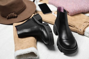 Siyah deri çizmeler, elbiseler ve aksesuarlar beyaz ahşap arka planda