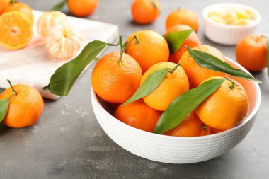 Gri masadaki yeşil yapraklı taze mandalinalar, yakın plan.