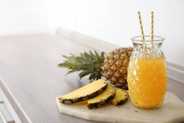Lezzetli ananas suyu ve ahşap masada taze meyve, metin için yer.