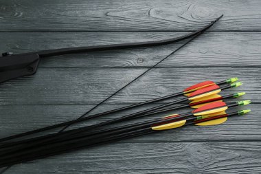 Plastik oklar ve gri ahşap masanın üzerinde düz bir şekilde duran fiyonk. Okçuluk spor ekipmanları
