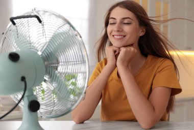 Kadın mutfaktaki pervaneden hava akışının keyfini çıkarıyor. Yaz sıcağı