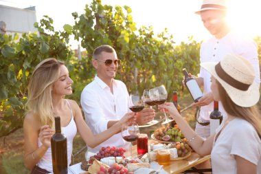 Şarap bardakları tutan ve üzüm bağında eğlenen arkadaşlar.