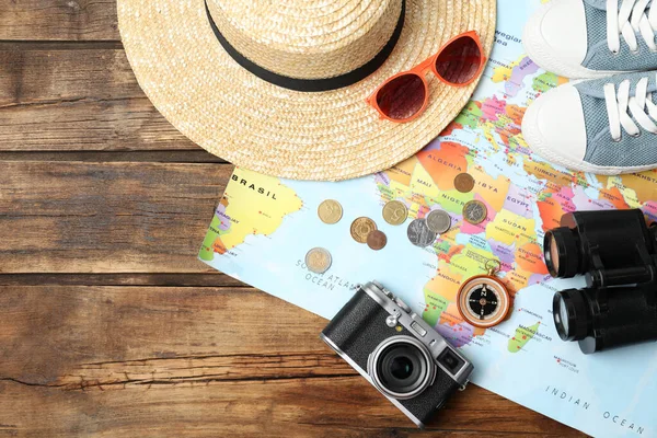 Flat lay composition with world map and different travel accessories on wooden table. Planning summer vacation trip