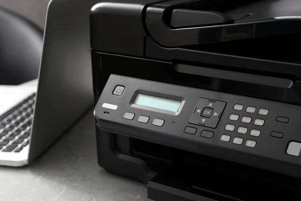 New modern printer and laptop on grey table, closeup