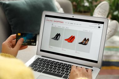 Kredi kartı olan bir kadın evde online alışveriş için dizüstü bilgisayar kullanıyor.