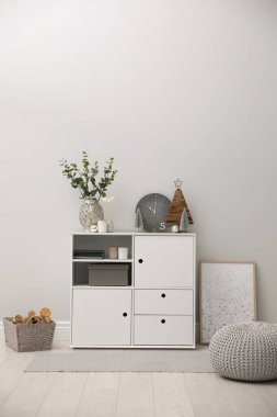 Işık duvarının yanında beyaz dolabı olan modern bir oda.