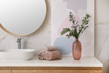 Güzel dalları ve tuvaletin yanında temiz havluları olan bir vazo. İç tasarım