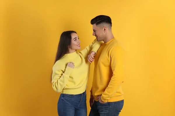 Pareja Feliz Vistiendo Suéteres Calientes Sobre Fondo Amarillo — Foto de Stock