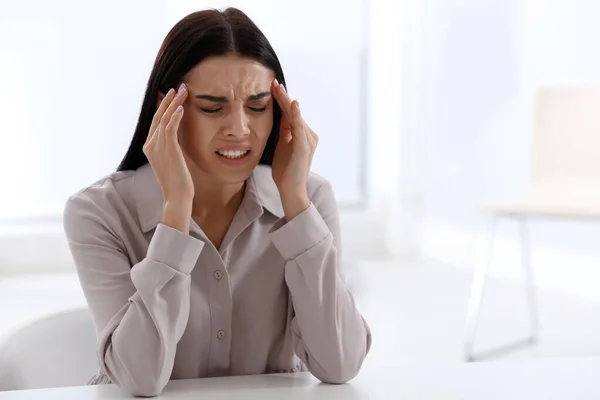 Stressed young woman at table in office