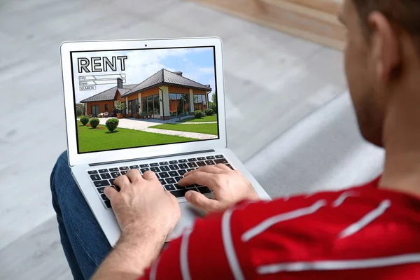 Man searching for house on rental property website via laptop, closeup